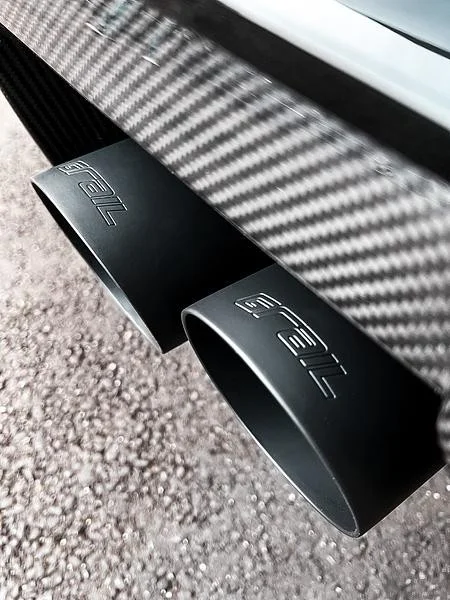 Nahaufnahme von Autoauspuffrohren mit Kohlefaserumrandung.