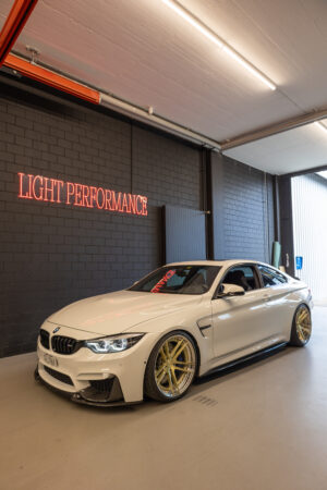 Weißes Auto in Garage mit Leuchtreklame.