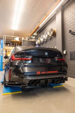 Schwarzes Auto in Werkstatt mit Felgen an der Wand.