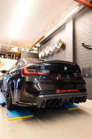 Schwarzes Auto in Garage mit Ersatzrädern an der Wand.