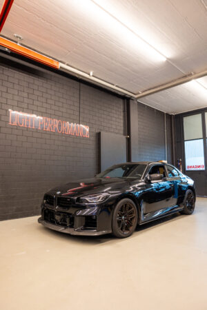 Schwarzes Auto in Werkstatt mit Performance-Logo